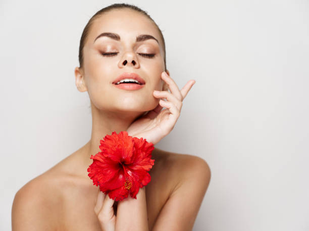 istock beautiful woman with bare shoulders closed eyes light background red flower 2191911288