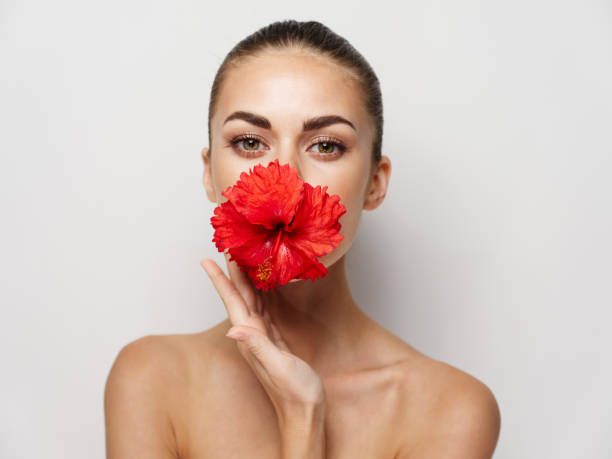 istock woman with bare shoulders red flower cropped view light background 2191911684