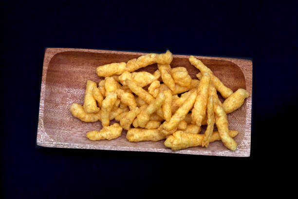 istock Cheese Puff Snacks on a wooden plate isolated on black background 2191911913