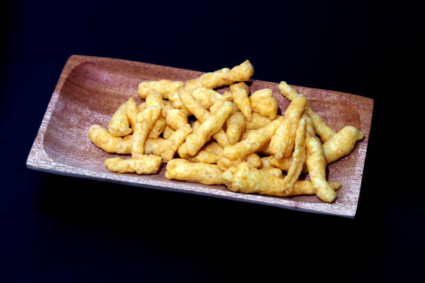 istock Cheese Puff Snacks on a wooden plate isolated on black background 2191911914