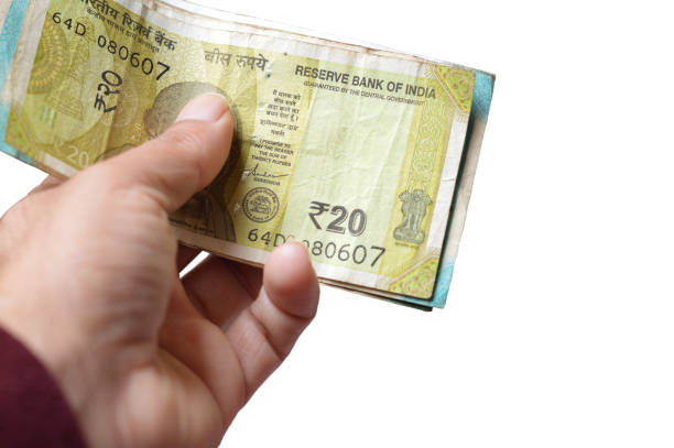 Cut out of one hands holding stack or pile of Indian Rupees currency paper notes cash stack with various denominations and  20 rupees on top, showing off a bundle of money, isolated over horizontal white background. Can be used as money lending, shopping, loans, payments, savings, investments, related backdrops with copy space.