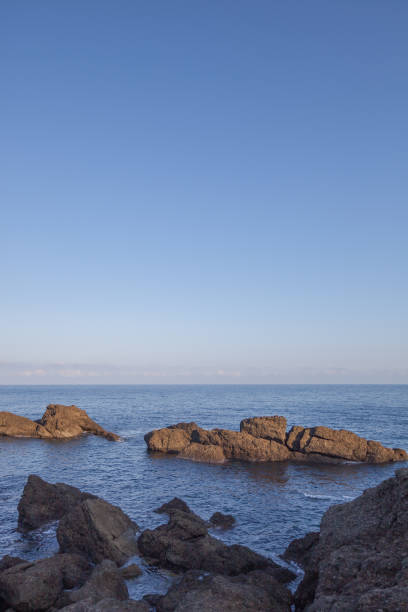 Under a clear blue sky, the coastline stretches out with a sparkling sea. A beautiful scenery with the soothing sound of waves and the refreshing breeze caressing your cheeks.