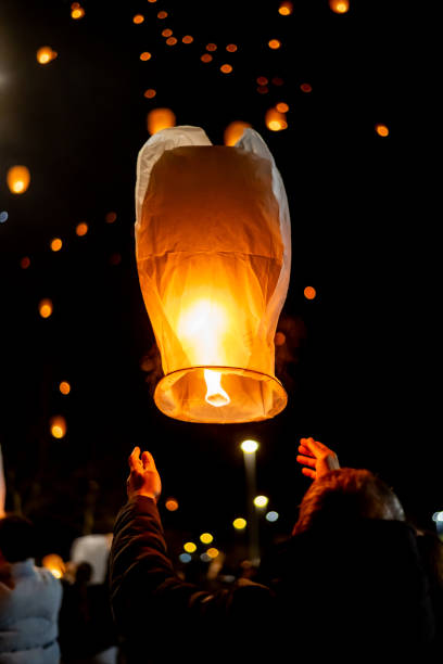 istock Releasing glowing lantern, individual merging with illuminated sky, surrounding floating lights generating mesmerizing nocturnal celebration scene 2191921585