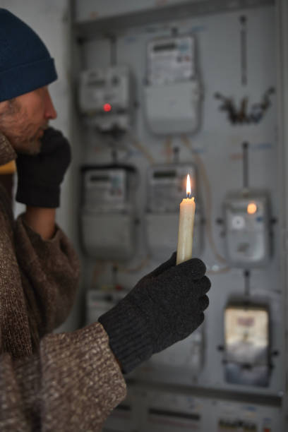 istock Checking the electricity power meter with a candle in cold winter days while there is power outage. 2191924966