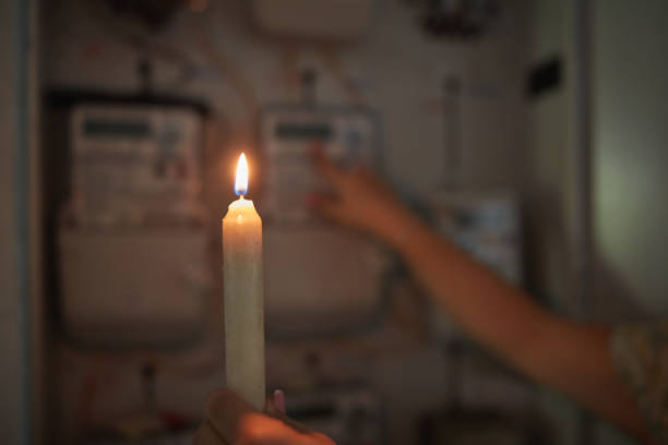 istock Checking the electricity power meter with a candle in cold winter days while there is power outage. 2191924975