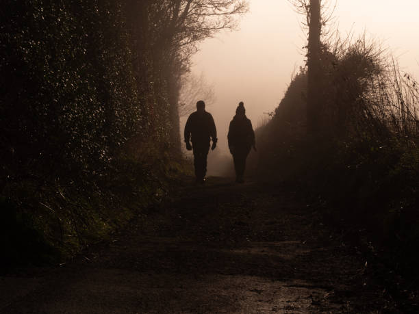 Couple waling in foggy misty pathway wide shot selective focus