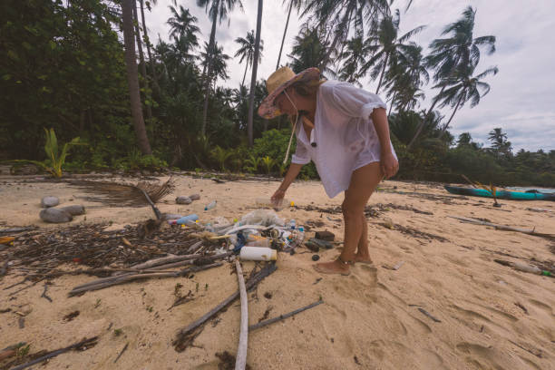 istock Woman Cleaning Beach of Plastic Waste Under Palm Trees 2191932178