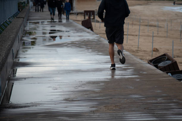 Rear view of an athlete running on wet wooden pier after the rain