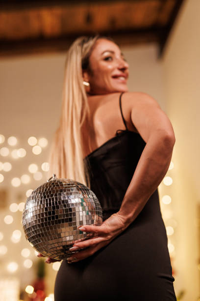 istock Woman holds a disco ball at a festive gathering with sparkling lights background 2191936344