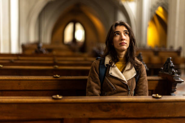 Portrait of young woman sitting alone and contemplating in cathedral