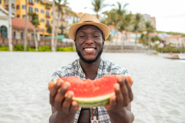 istock Smiling Young Black Man Enjoying Watermelon on Beach 2191943625