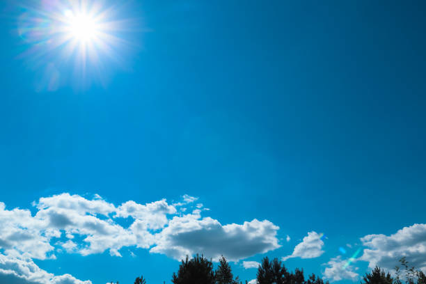 Sunny day. Blue sky with white clouds and sun. Sunburst With Lens Flare. Heavens with bright weather, summer season outdoor. Sky clouds with bright sun rays.