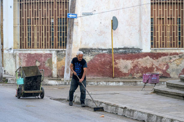 Santa Clara, Cuba - December 26, 2024: Senior Cuban man working as street sweeper.