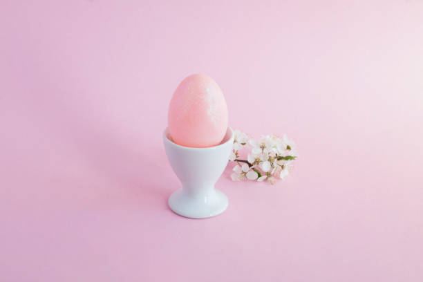 istock Pink easter egg in the white eggcup on the pink  background. Close-up. 2191959260