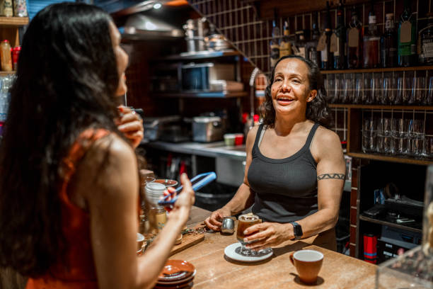 istock Aboriginal Waitress Shares Friendly Conversation While Serving Customer at Cafe 2191960626