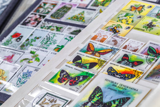 istock Philately.Collection of stamps and magnifying glass.Postage stamps range with different species of butterflies.A page of storage book album for storing old postage stamps. 2191962209