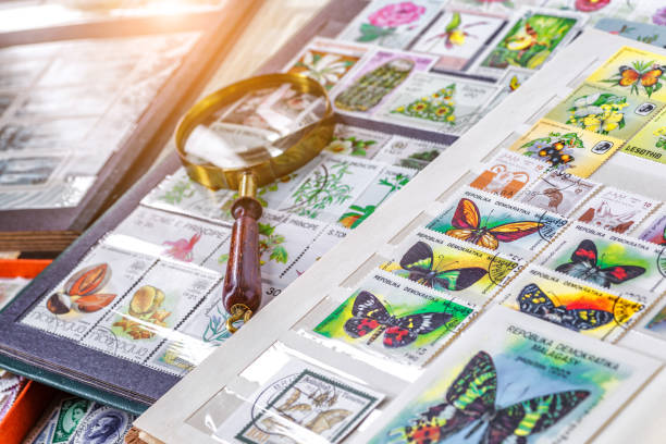 istock Philately.Collection of stamps and magnifying glass.Postage stamps range with different species of butterflies.A page of storage book album for storing old postage stamps. 2191962211