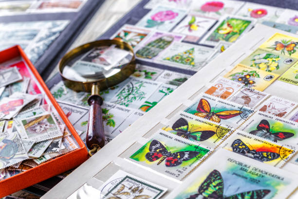 istock Philately.Collection of stamps and magnifying glass.Postage stamps range with different species of butterflies.A page of storage book album for storing old postage stamps. 2191962214