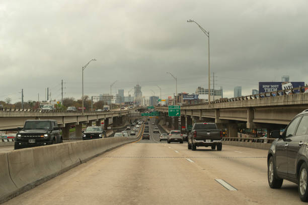 A first person perspective of travelling down the IH 35 south lower deck in Austin, Texas USA near the 38th 1/2 street exit depiction traffic conditions and general atmosphere at this time of year. large buildings of downtown can be seen in the background. Photo taken around 1130 am on december 15th from the passenger seat of a moving vehicle.