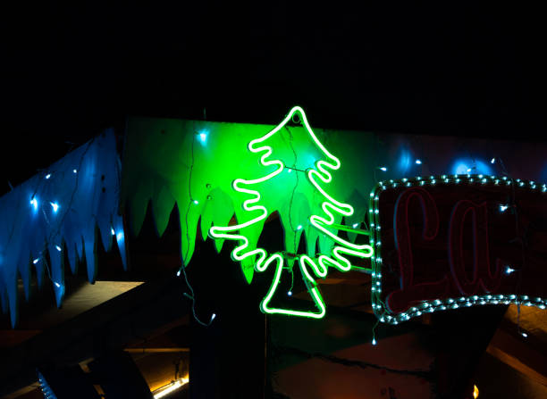 A bright neon green Christmas tree sign at Colmar, France christmas market adds a festive touch to a holiday display.