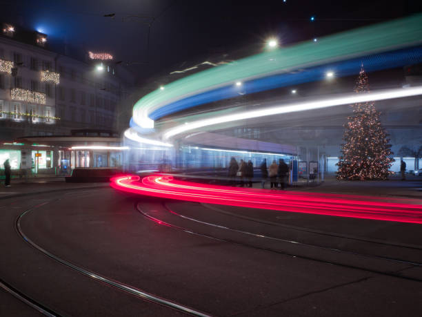 Light trails from a moving tram in Zurich at night, with a Christmas tree in the background.