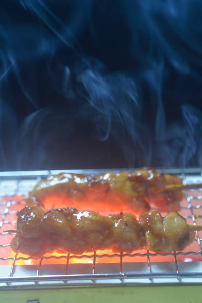 Grilling yakitori on a charcoal grill with smoke rising