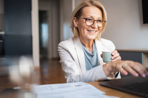 istock Smiling mature woman enjoying coffee while working on laptop 2191978242