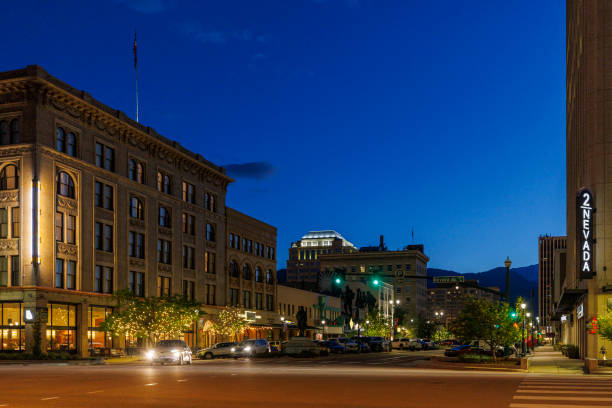 Nightlife awakens in downtown Colorado Springs, CO. Illuminated East Pikes Peak Avenue with hotels and shops stretching car traffic Colorado Springs, Colorado, USA - May 31, 2024: A vibrant nighttime street scene in downtown Colorado Springs, Colorado. Historic buildings with ornate architecture line the street, illuminated against the deep blue evening sky. Trees adorned with twinkling lights add a festive atmosphere. Cars and pedestrians move along the wide avenue, while mountains loom in the distant background colorado springs city stock pictures, royalty-free photos & images