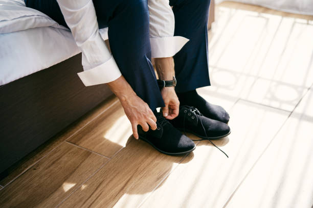 istock Groom laces up his shoes while sitting on the bed. Cropped. Faceless 2191985376