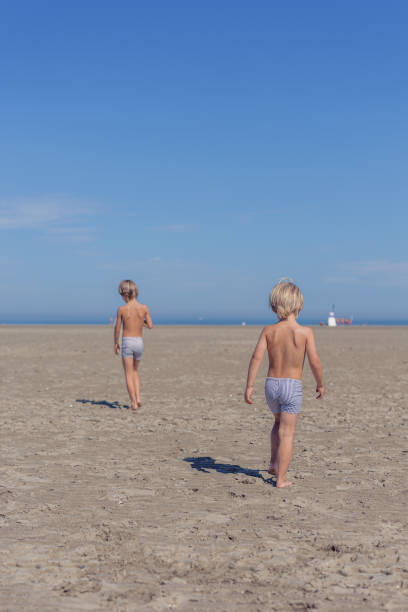 Two Brothers Walking Towards the Horizon on Sandy Beach in Knokke-Heist, Flanders, Belgium