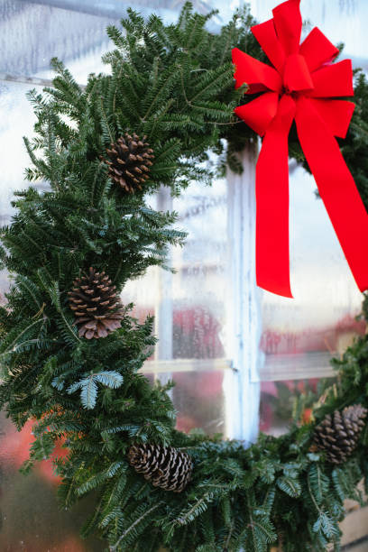 istock Festive evergreen wreath with pinecones and a red bow on a window 2191987762