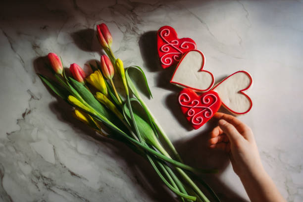 Hand reaching for heart cookies and tulips