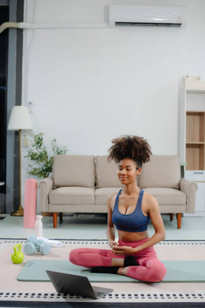 istock African Woman Doing Yoga and Watching Online Tutorials on Laptop, Training 2191991051