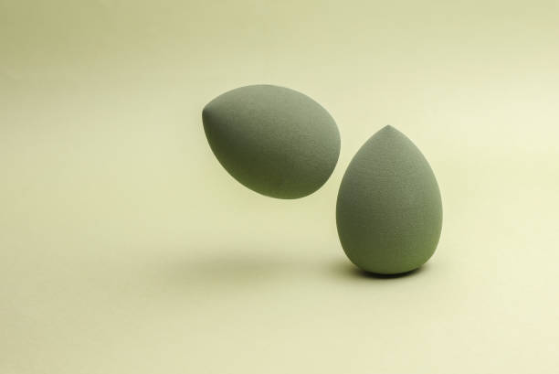 istock Floating Egg makeup sponge. Blender for foundation on green background. Minimal beauty concept 2191996816