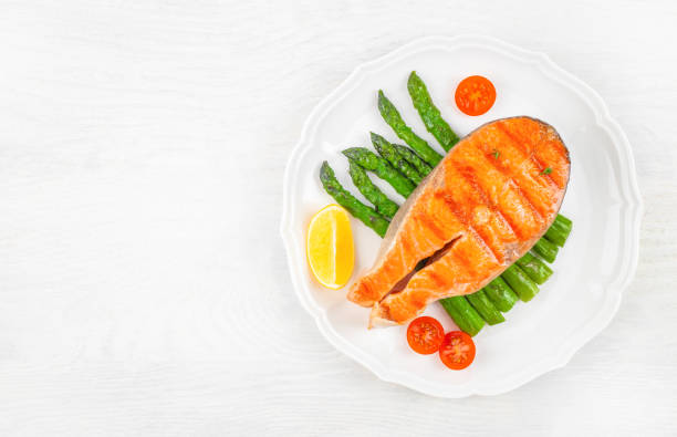Grilled salmon steak with asparagus and tomatoes cherry on a white plate. top view. copy space.