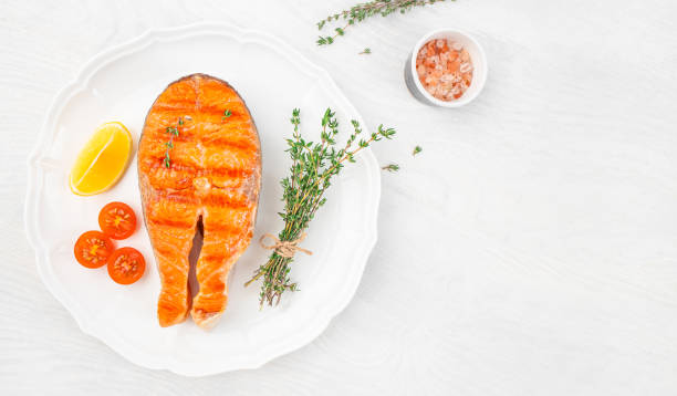 istock salmon steak on plate with spices thyme baked on a grill on a white background top view. copy space 2192009784