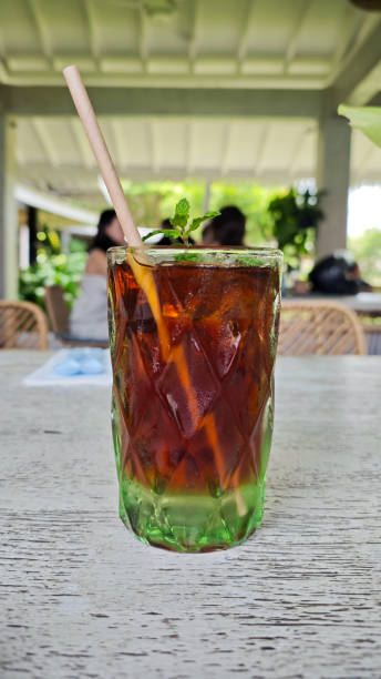 istock Refreshing Iced Black Tea with Mint Garnish in Textured Glass on Rustic Wooden Table at an Outdoor Cafe Setting 2192009824