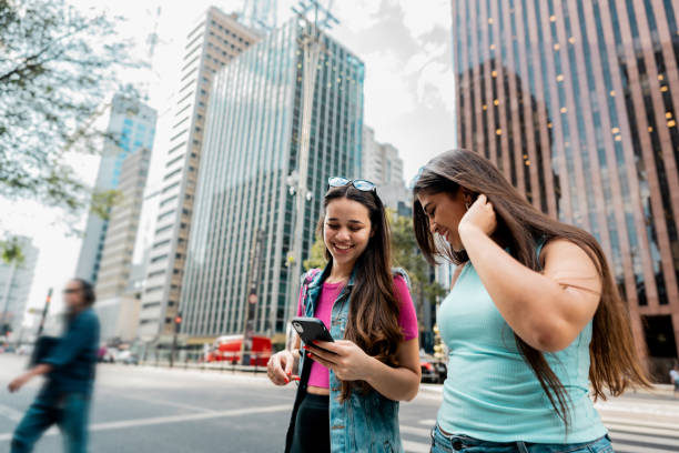 istock Young friends using the mobile phone while walking in the street 2192012724