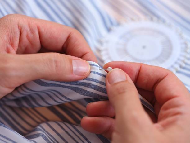 istock Woman hands using a sewing push pin on the striped clothes. 2192012770