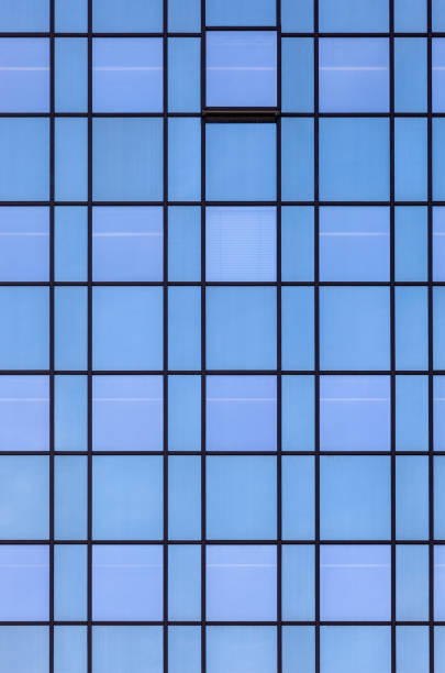 glass facade of an office building with reflection of blue sky