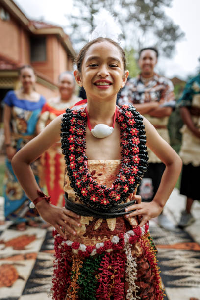 istock Cute pacific islander girl in traditional clothes posing for camera while standing in front of her family 2192016635