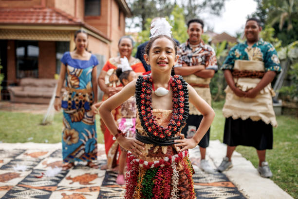 istock Cute pacific islander girl in traditional clothes posing for camera while standing in front of her family 2192016637