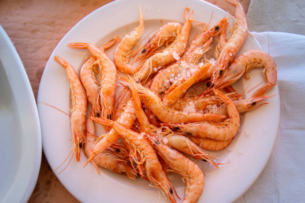 Fresh tiger shrimp displayed on a rustic wooden counter at a farmer's market. The vibrant seafood is surrounded by natural ingredients, evoking a healthy, sustainable lifestyle