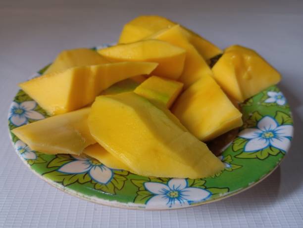 istock A plate filled with ripe mango slices is placed on a floral-patterned green plate. 2192029461