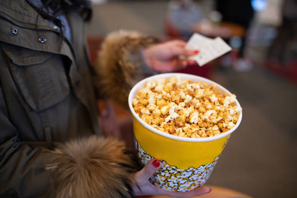 Woman holding popcorn and movie ticket