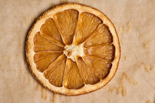 Closeup of slices of dried oranges on brown baking paper, flat lay