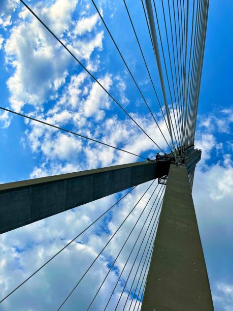 istock bridge structure consisting of steel cables and a gray concrete support against a background of blue sky and clouds from the perspective of a frog 2192030338