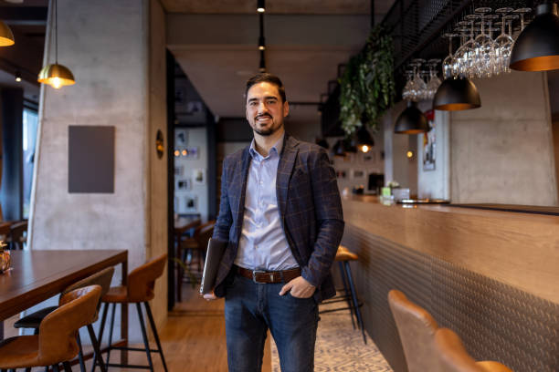 Restaurant manager holding laptop and smiling at camera