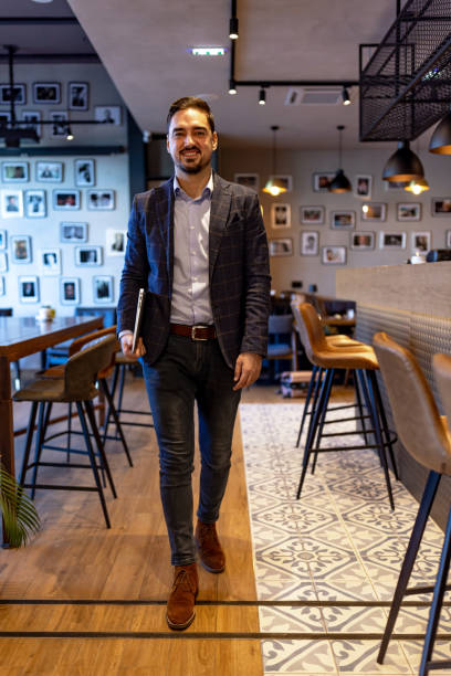 istock Businessman walking in a modern cafe holding a laptop 2192037503