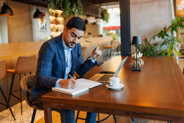 istock Businessman taking notes and working on laptop in a cafe 2192037592